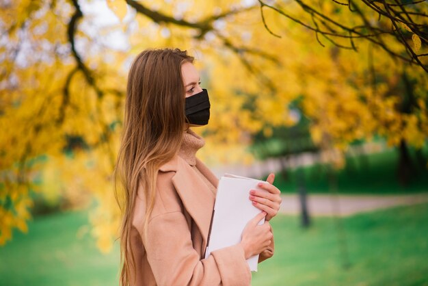 Une jeune femme se protégeant du virus corona en marchant dans un parc