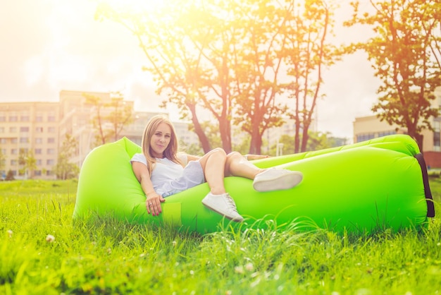 Jeune femme se reposant sur un canapé d'air dans le parc.. lamzac