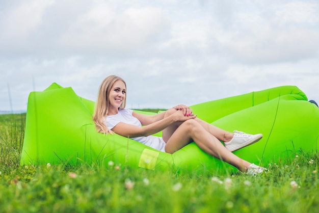 Jeune femme se reposant sur un canapé d'air dans le parc