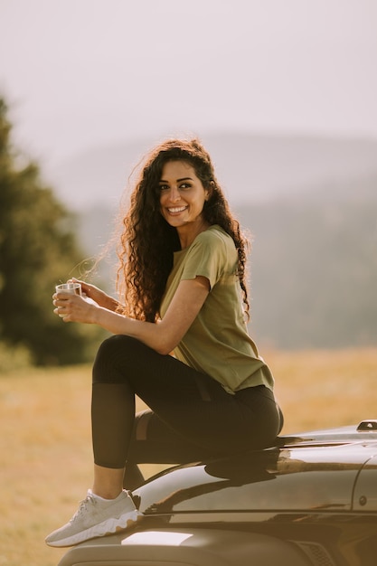 Jeune femme se reposant sur un capot de véhicule tout-terrain à la campagne