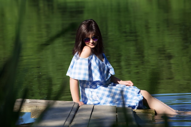 Jeune femme se reposant sur un pont en bois et mouille les pieds dans la rivière