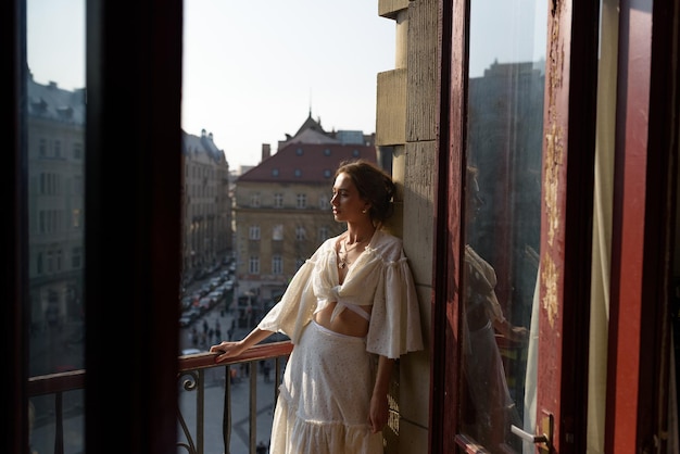 Une jeune femme se repose sur le balcon de son appartement avec vue sur la vieille ville