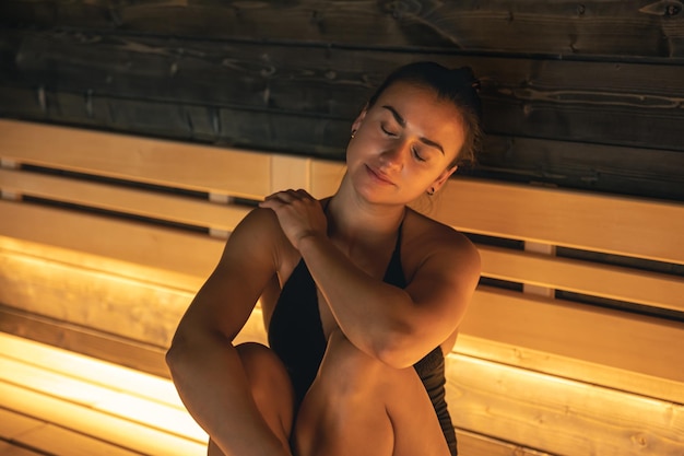 Une jeune femme se repose seule dans un sauna