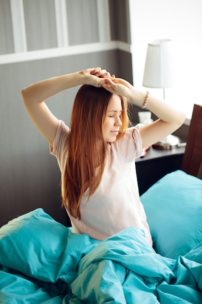 Jeune femme se réveillant et s'étirant dans son lit