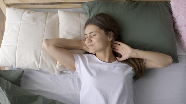 Photo une jeune femme se réveille de mauvaise humeur dans un lit inconfortable à la maison