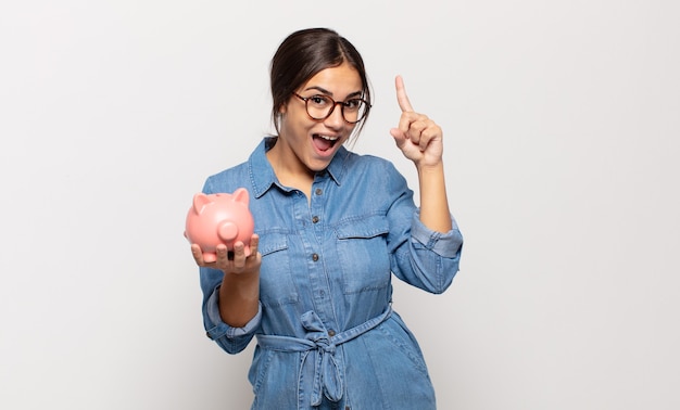 Jeune femme se sentant comme un génie heureux et excité après avoir réalisé une idée, levant joyeusement le doigt, eureka!