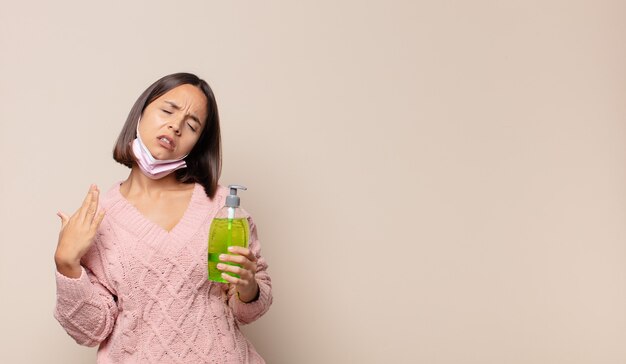 Jeune femme se sentant stressée, anxieuse, fatiguée et frustrée tenant une bouteille antibactérienne