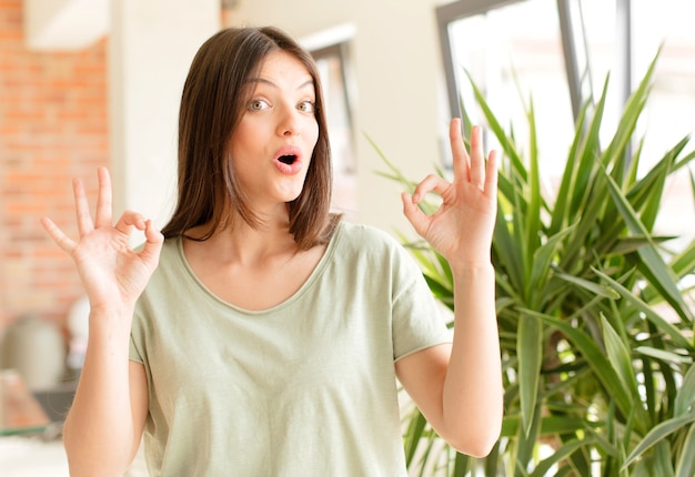 Photo jeune femme se sentir choqué étonné et surpris montrant son approbation faisant signe correct avec les deux mains