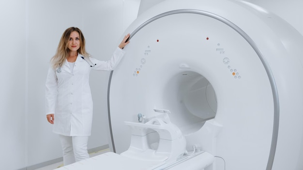 Une jeune femme se tient à côté d'un appareil IRM dans un laboratoire moderne de la clinique Photo panoramique