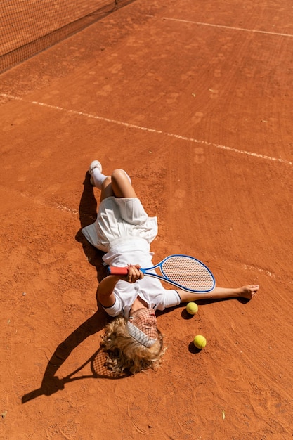 une jeune femme se trouve sur un court de tennis sur gazon portant un costume de sport blanc