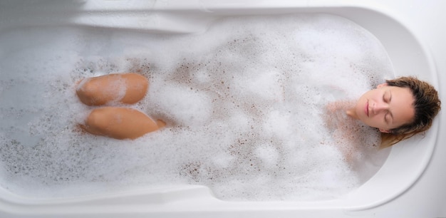 Photo une jeune femme se trouve dans une vue de dessus de bain de mousse savonneuse