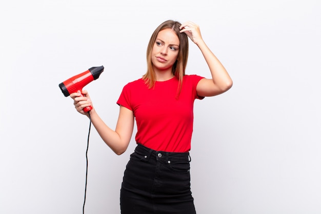 jeune femme avec sèche-cheveux, perplexe et confus