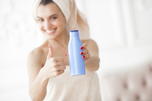 Jeune femme séduisante appliquant la crème après douche