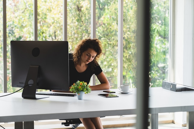 Jeune femme séduisante assise et prendre note des affaires tout en travaillant dans un bureau