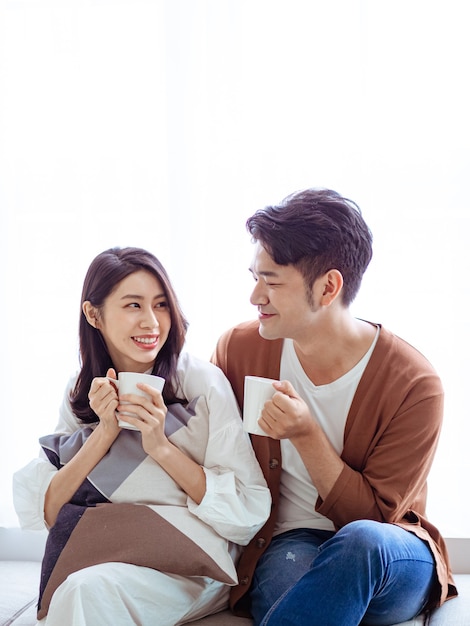 Une jeune femme séduisante et un bel homme aiment passer du temps ensemble à la maison avec une tasse de café dans les mains.