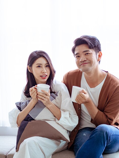 Une jeune femme séduisante et un bel homme aiment passer du temps ensemble à la maison avec une tasse de café dans les mains.