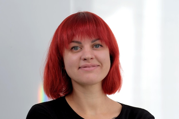 Une jeune femme séduisante avec une coiffure courte orange dans un T-shirt noir et un jean posant en studio sur fond blanc