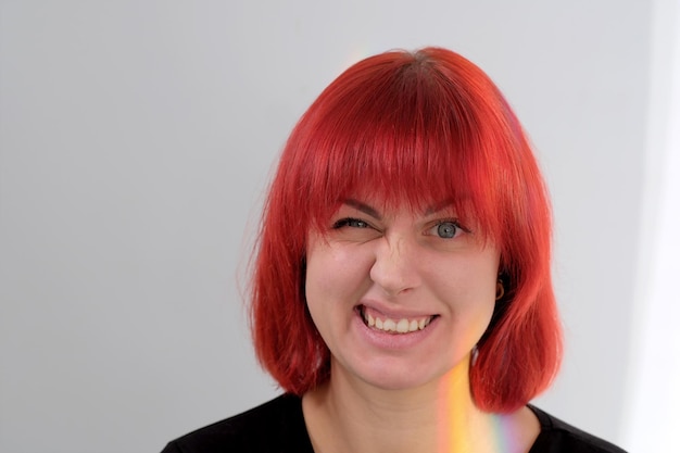 Une jeune femme séduisante avec une coiffure courte orange dans un T-shirt noir et un jean posant en studio sur fond blanc