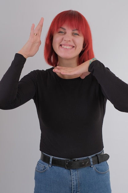 Une jeune femme séduisante avec une coiffure courte orange dans un T-shirt noir et un jean posant en studio sur fond blanc