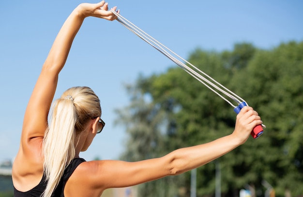 Jeune femme séduisante avec un corps mince parfait faisant des étirements avec une corde à sauter. Photo en gros plan