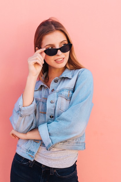 Une jeune femme séduisante furtivement à travers des lunettes de vue permanent sur fond de pêche