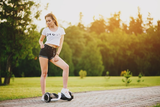 Jeune femme séduisante avec hoverboard à l'extérieur dans le parc au coucher du soleil. Tonifié