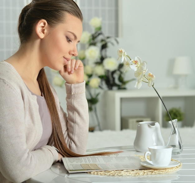 Jeune femme séduisante avec livre et tasse de café