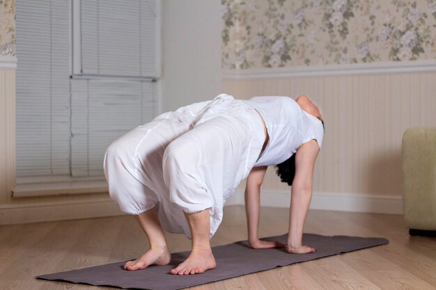 Jeune femme séduisante pratiquant le yoga portant des vêtements de sport séance de méditation intérieur de la maison