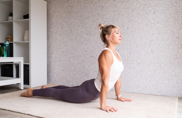 Jeune femme séduisante pratiquant le yoga tout en portant des vêtements de sport à l'intérieur