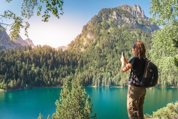 Jeune femme séduisante prenant une photo avec son téléphone portable en randonnée dans un magnifique paysage de lac en été Concept de destination de voyage découverte