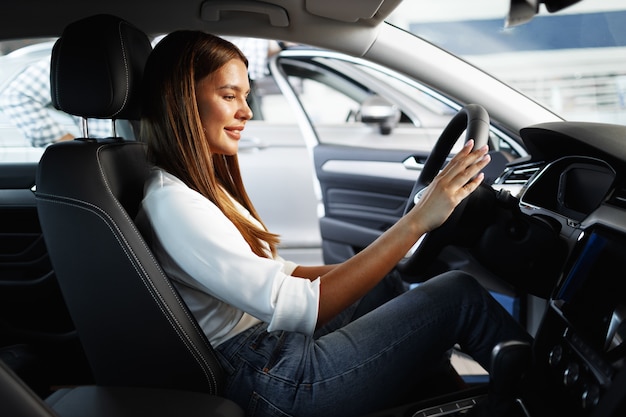 Jeune Femme Séduisante à La Recherche D'une Nouvelle Voiture Dans Une Salle D'exposition De Voiture