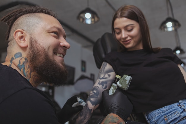 Jeune femme séduisante se faisant tatouer par un tatoueur professionnel