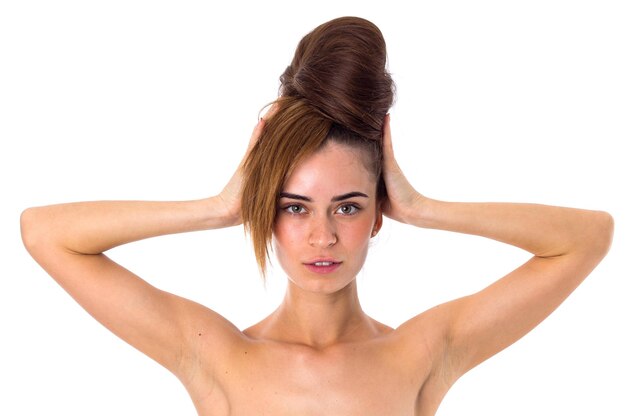 Jeune femme séduisante avec ses longs cheveux en chignon touchant la tête sur fond blanc en studio