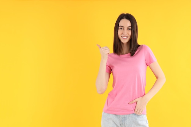 Jeune femme séduisante en t-shirt sur fond jaune