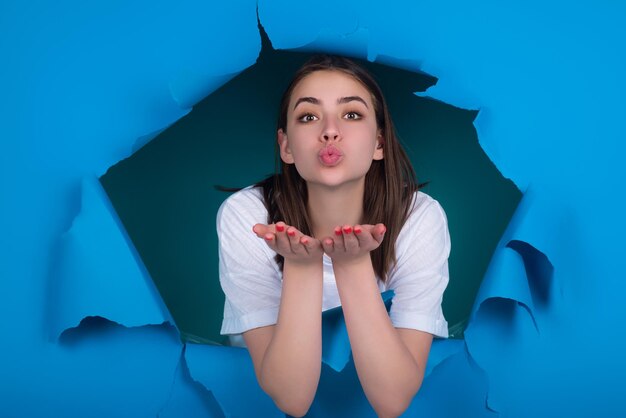 Une jeune femme sensuelle envoie un baiser d'air isolé sur un studio de papier bleu un baiser de trou pour vous une femme sensationnelle envoie