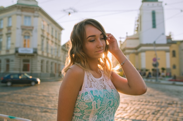 Jeune femme sensuelle en robe de dentelle posant dans les rayons du soleil