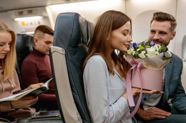 Jeune femme sentant des fleurs dans un avion de passagers