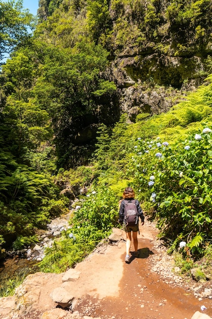 Une jeune femme sur le sentier à côté de la cascade de Levada do Caldeirao Verde Queimadas Madeira