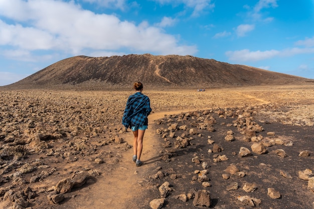 Une jeune femme sur le sentier menant au cratère du volcan Calderon Hondo près de Corralejo, côte nord de l'île de Fuerteventura, Îles Canaries. Espagne