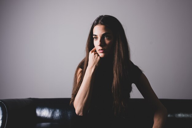 Une jeune femme sérieuse assise sur un canapé