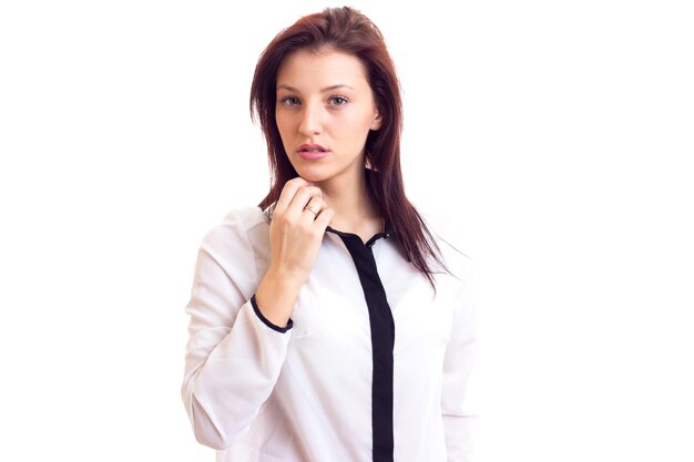 Jeune femme sérieuse en chemise blanche et noire avec des cheveux foncés sur fond blanc en studio