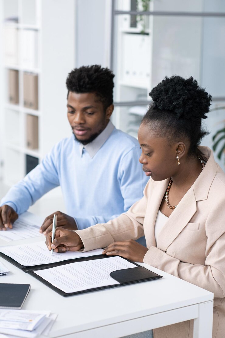 Jeune femme sérieuse d'origine africaine signant des documents financiers
