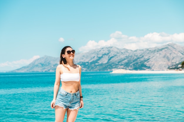 jeune femme seule le long de la mer bleue avec des montagnes sur fond