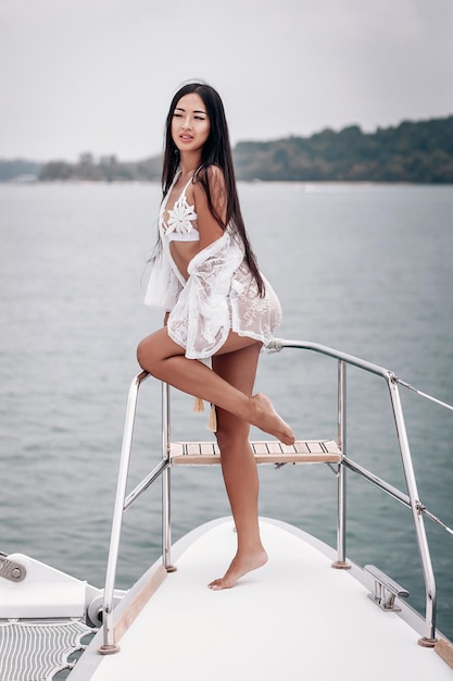 Jeune femme sexuelle avec une jambe surélevée, vêtue d'un bikini blanc, pose sur le yacht, portrait