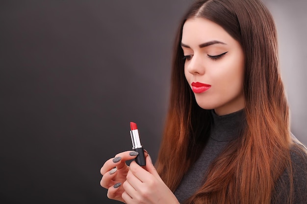 Jeune femme sexy asiatique aux cheveux noirs à l'aide de rouge à lèvres rouge