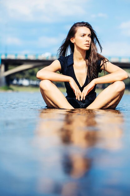 Jeune femme sexy assise dans l'eau