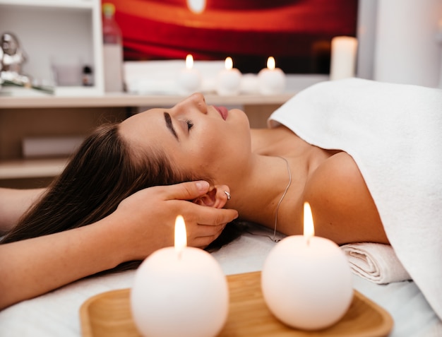 Jeune femme sexy au spa reçoit un massage facial.