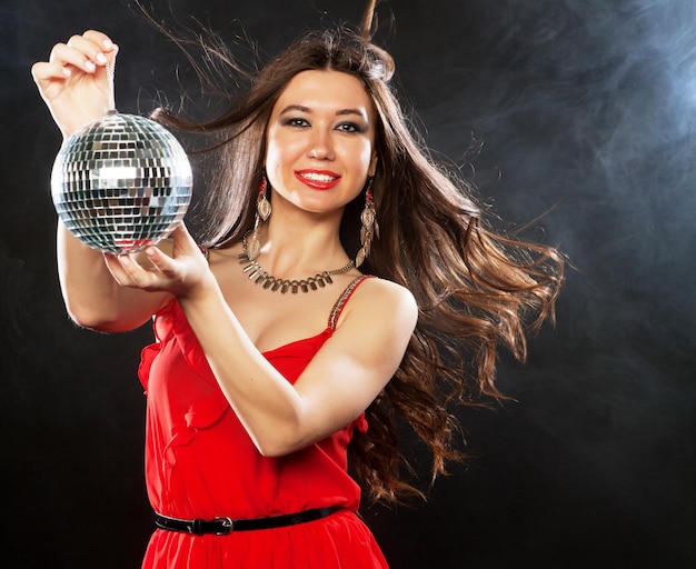 Jeune femme sexy en dres rouge gardant une boule disco