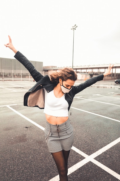 Jeune femme sexy avec un masque blanc sur un parking