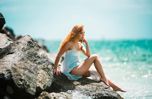 Une jeune femme sexy en mer, une plage d'été, une fille sensuelle, une fille en robe blanche en vacances sur une plage tropicale.